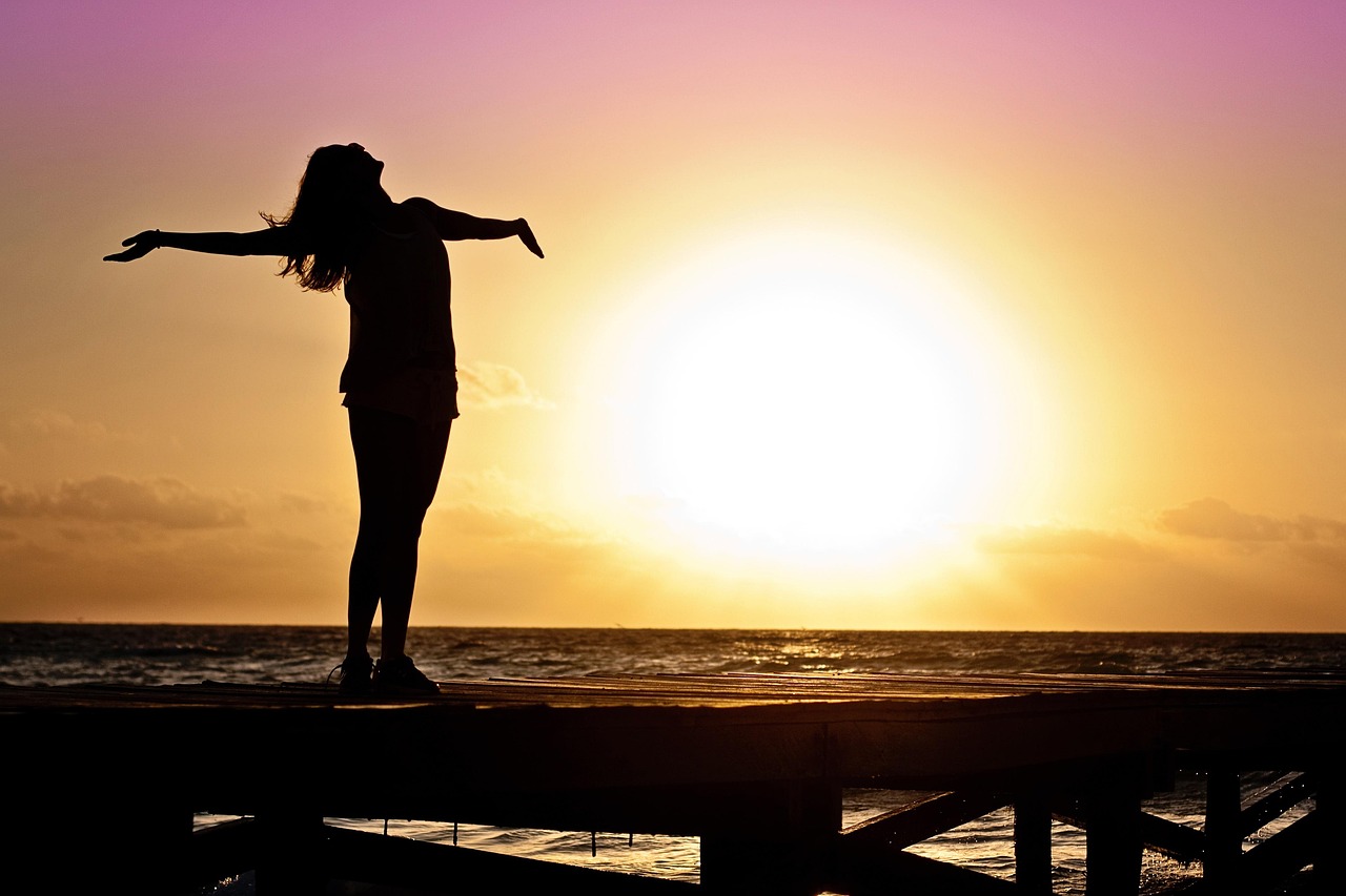 Woman at sunset with open arms, symbolizing healing, childfree not by choice, and life after infertility.